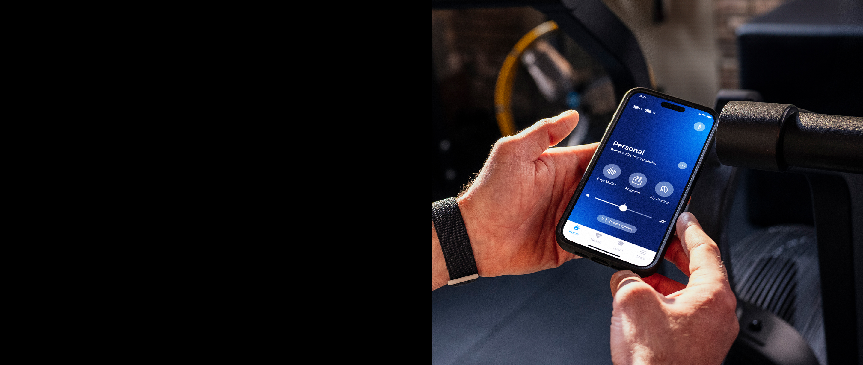 Hands holding a cell phone with the My Starkey app on screen.