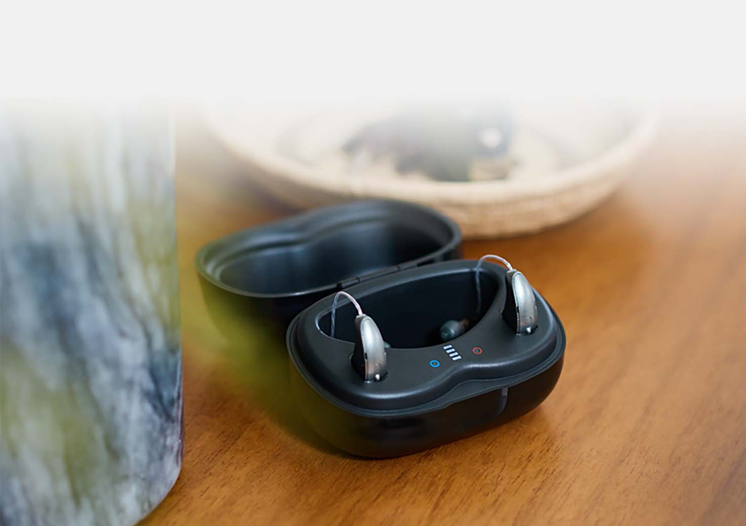 StarLink Charger sitting on a desk open with RIC hearing aids inside.