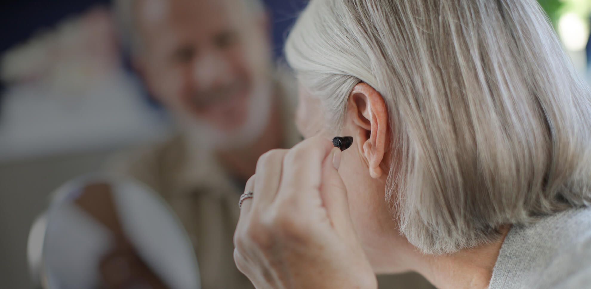 Woman putting a hearing aid in her ear.