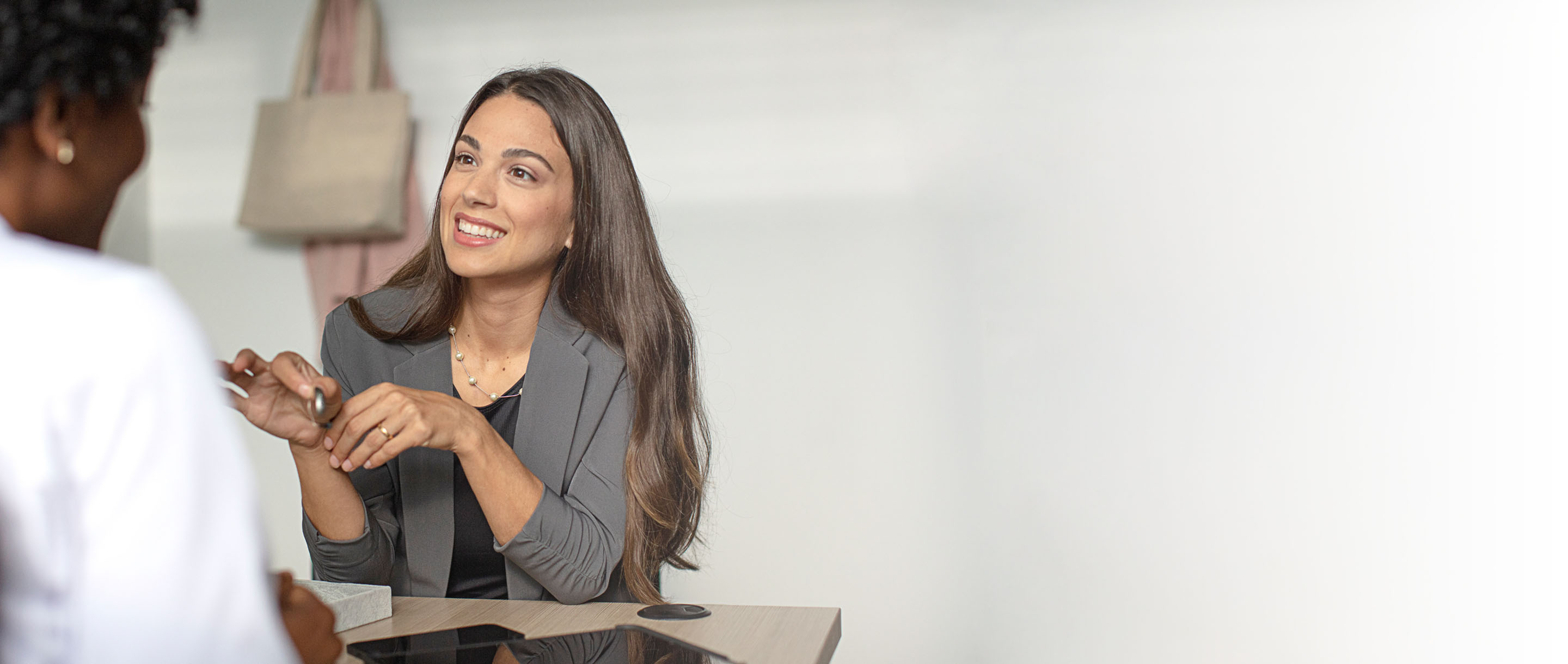 Woman talking to a hearing professional and holding a RIC hearing aid.